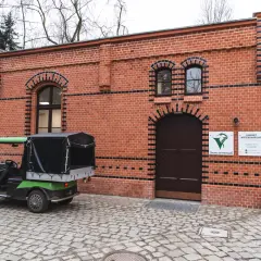 Zielony wózek golfowy przed ceglanym budynkiem gabinetu weterynaryjnego w zoo.