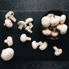 Świeże pieczarki na czarnej desce. Czy pieczarki są szkodliwe? Te wyglądają apetycznie i są bezpieczne do jedzenia.