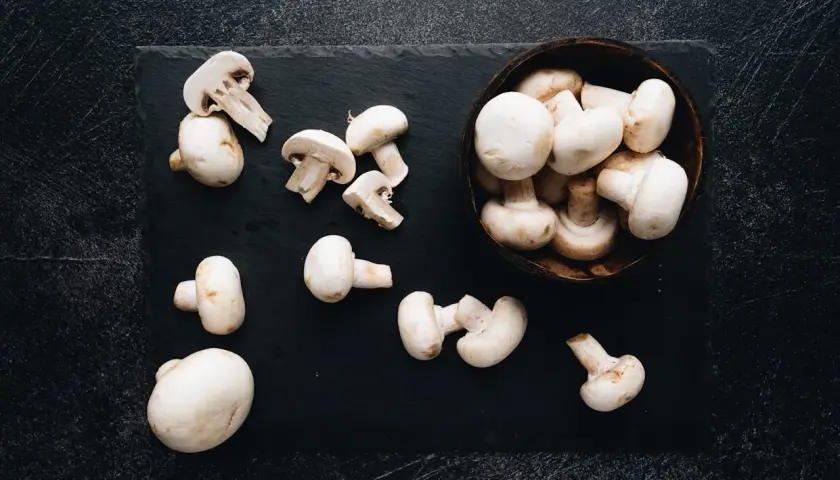 Świeże pieczarki na czarnej desce. Czy pieczarki są szkodliwe? Te wyglądają apetycznie i są bezpieczne do jedzenia.
